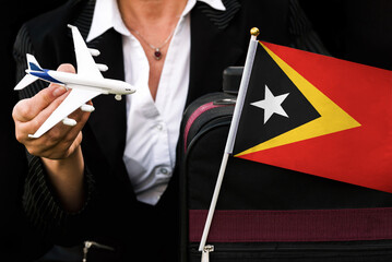 business woman holds toy plane travel bag and flag of East Timor . 