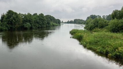 Fototapeta na wymiar Light summer rain and its drops falling into the river water. Calm landscape of Lithuania
