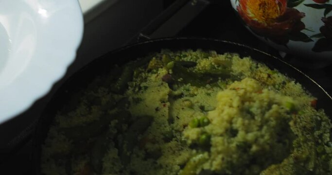 Vegetables, green beans, couscous and curia are placed on a plate. Medium plan