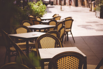 Empty elegant old-fashioned coffee terracce with tables and chairs on an old city street....