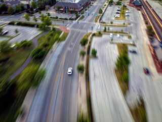 Long exposure aerial shot of fast riding white car on city urban street