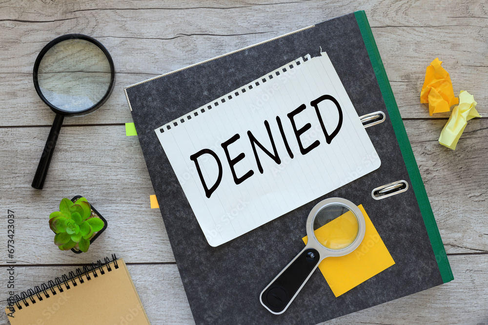 Poster denied. text on a notepad on a gray folder with documents