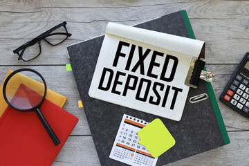 FIXED DEPOSITS - text on a notebook on a folder. red notepad. magnifying glass