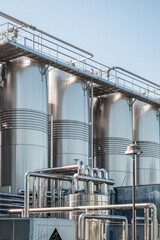 Stainless group vertical steel storage tanks for wine fermentation and maturation in modern winery factory production. Industrial and technology background. Vertical orientation