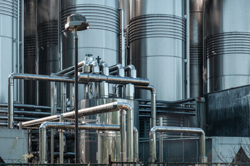 Stainless steel pipes and storage tanks. Industrial wine production, metal pipeline in winery fermentation and maturation process. Industrial and technology background