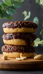 Chocolate donuts sprinkled with crushed nuts on a black table