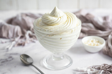 Creamy, sweet cream for cakes. A delicate, vanilla cream for cupcakes. Sweet dessert: creamy cream in a beautiful cup on a white background. Close-up