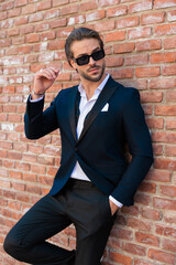 Obraz premium sexy elegant man with sunglasses holding hand in pocket and looking to side
