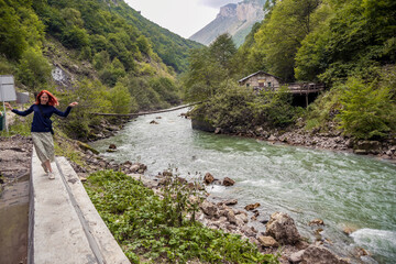 Girl walking near the mountain river, awesome scenery, lots of lush greenery. Caucasus, Russia