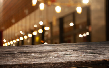 Wooden table top on blurred cafe showcase with light bulb. Background for product display montage...