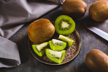Ripe sliced kiwi fruit and whole on a plate on the table