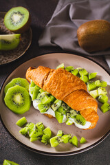 Croissant sandwich kiwi fruit and yogurt on a plate on the table vertical view