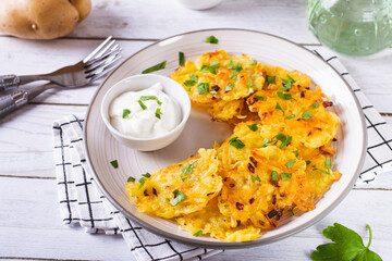 Traditional potato latkes with greens and sauce on a plate on the table