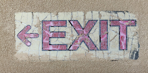 old faded EXIT sign affixed to stucco wall