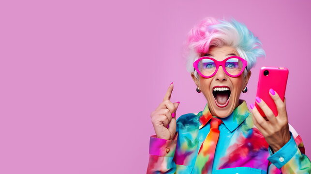 Happy stylish senior woman using cellphone on pink color background. Online Shopping. Sale