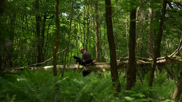 A man looking like he may be urinating in a forest