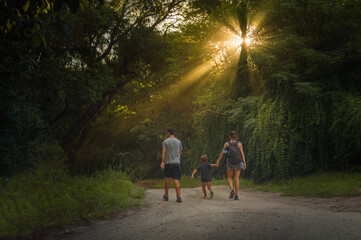 Small family walking down a hill at sunset with sun rays illuminating them