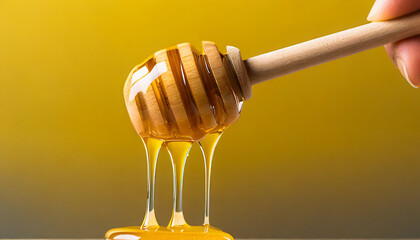 Honey dripping from wooden honey dipper over yellow background. Sweet bee product for your design with copyspace. .