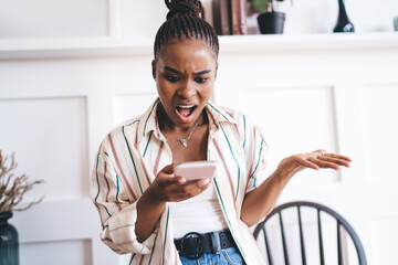 Amazed black woman browsing social media on smartphone