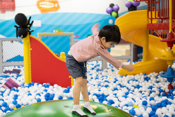 Little boy practices standing on a big inflatable ball.