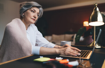 Middle aged woman working on laptop in living room