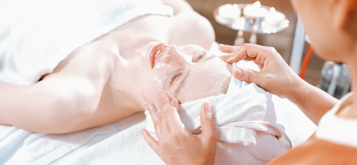Portrait of beautiful caucasian woman having facial massage with homemade facial mask while lies on...