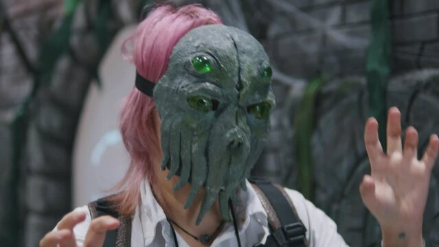 Girl posing in Cthulhu mask at anime cosplay gaming expo convention festival.