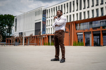 A man standing in front of a building talking on a cell phone. A Busy Professional in Front of a Modern Office Building