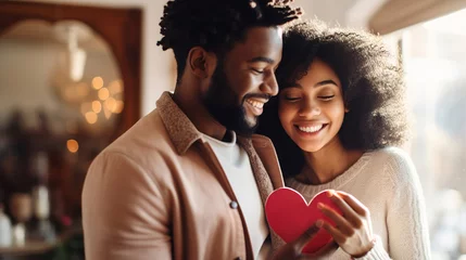 Foto op Canvas Smiling afro american couple hugging each other and holding a card given for Valentine's Day. Relationship concept © Irina Sharnina