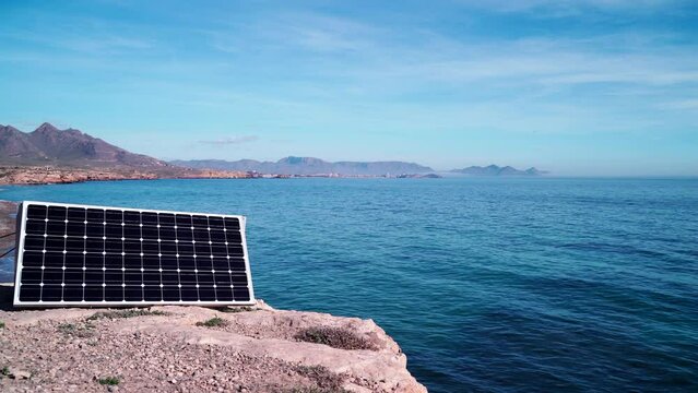 Portable solar panel, photovoltaic cell working outdoors on seashore. Renewable free energy.
