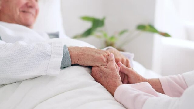 Love, comfort and senior couple holding hands in bedroom at nursing home for support in marriage. Compassion, sweet and closeup of elderly man and woman in retirement with affection at modern house.