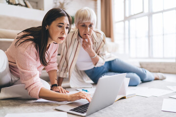 Focused multiethnic coworkers working on netbook sitting on floor