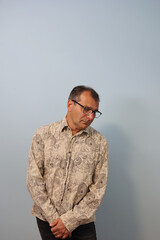 Portrait of sad adult man looking at the floor on flat gray background
