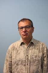 Mature man wearing eyeglasses showing skeptical face expression.