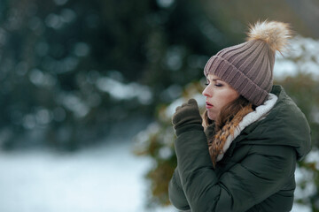 sad 40 years old woman outdoors in park in winter coughing