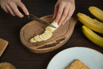 Woman slices banana for breakfast.