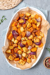 Oven-baked vegetables on a baking sheet. Baked pumpkin, potatoes, carrots and onions. Cooking dinner in the oven. Vegetarian food in the oven.