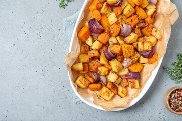 Oven-baked vegetables on a baking sheet. Baked pumpkin, potatoes, carrots and onions. Cooking dinner in the oven. Vegetarian food in the oven.