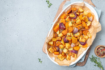 Oven-baked vegetables on a baking sheet. Baked pumpkin, potatoes, carrots and onions. Cooking dinner in the oven. Vegetarian food in the oven. - obrazy, fototapety, plakaty