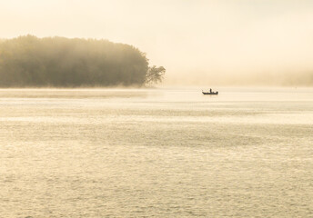 Fisherman in water of Upper Mississippi on calm misty morning near Dubuque in Iowa