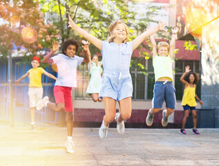 Fototapeta na wymiar Group of positive playful kids jumping outdoors. Happy children on summer vacation.
