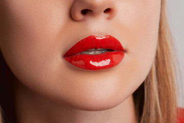 Close up macro female plump lips with red gloss. Beauty fashion portrait personal care and make up