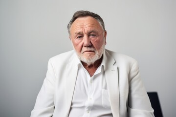 Portrait of an old man in a white jacket on a gray background