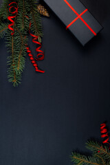 A Christmas tree, decorations, lights and a gift box on a black background. Top view.