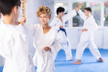 Fototapeta na wymiar Willing junior attendee of karate classes fighting with his opponent in sports hall