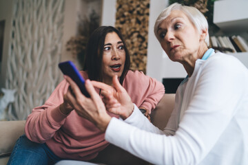 Multiracial aged girlfriends chatting while messaging on smartphone