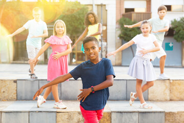 Children exercising contemporary dance moves during their outdoor rehearsal. - obrazy, fototapety, plakaty