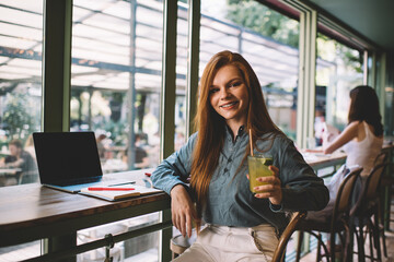 Smiling woman with glass of juice sitting in cafe