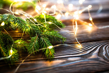 pruce branches adorned with twinkling Christmas lights on a festive wooden background. holiday...