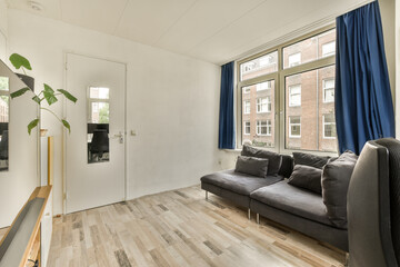a living room with wood flooring and blue drapes on the window in the photo is taken from outside